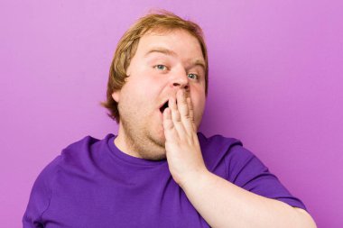 Genç otantik kızıl saçlı şişman adam esniyor. Ağzı eliyle kapatan yorgun bir jest yapıyor..