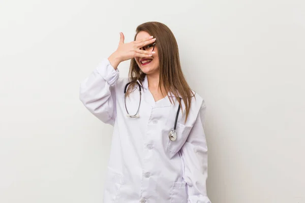 Jonge Dokter Vrouw Tegen Een Witte Muur Knipperen Camera Door — Stockfoto