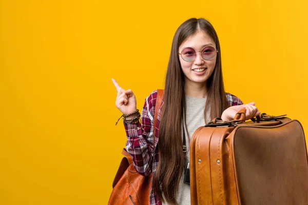 年轻的亚洲女人拿着一个手提箱 高兴地微笑着 无时无刻不带着食指 — 图库照片