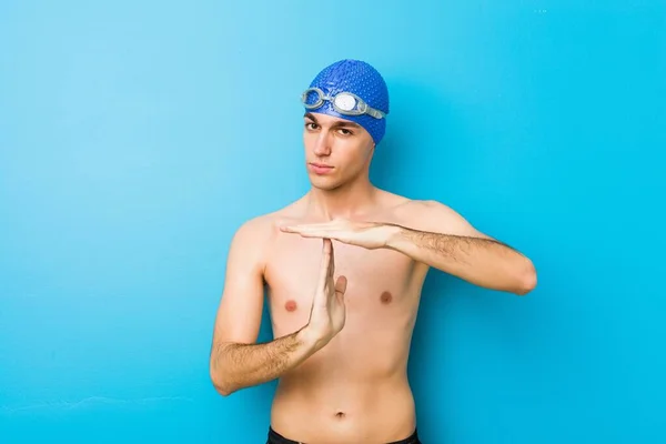 Young swimmer man showing a timeout gesture.
