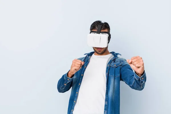 Young south-asian man playing with virtual reality glasses