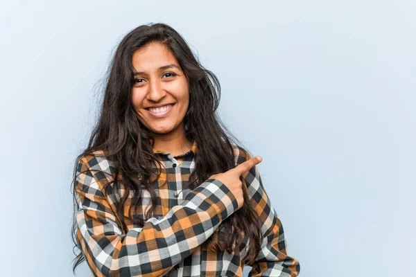 Genç, havalı Hintli kadın gülümsüyor ve boş alanda bir şeyler gösteriyor..