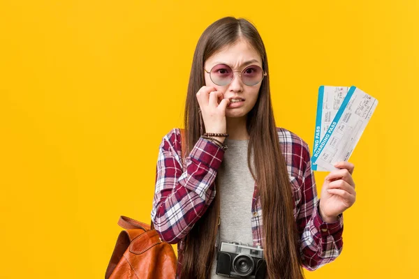 Elinde uçak bileti olan genç Asyalı bir kadın tırnaklarını yiyor, gergin ve çok endişeli..