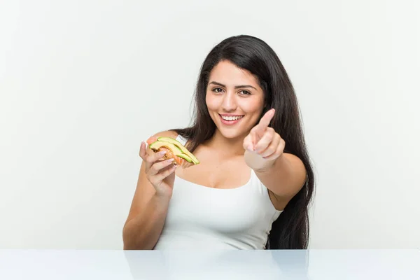 Junge Hispanische Frau Hält Einen Avocado Toast Und Lächelt Fröhlich — Stockfoto