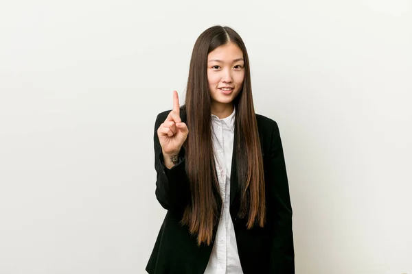 Young pretty chinese business woman showing number one with finger.