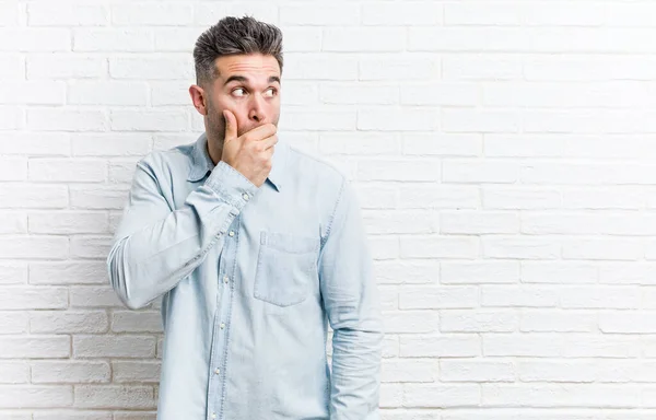 Mladý Pohledný Muž Proti Cihlové Zdi Zamyšlený Při Pohledu Kopii — Stock fotografie