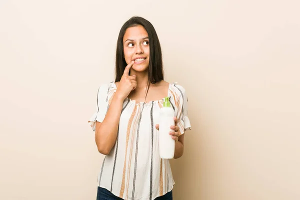 Junge Hispanische Frau Mit Einer Cremeflasche Entspannt Über Etwas Nachdenkend — Stockfoto