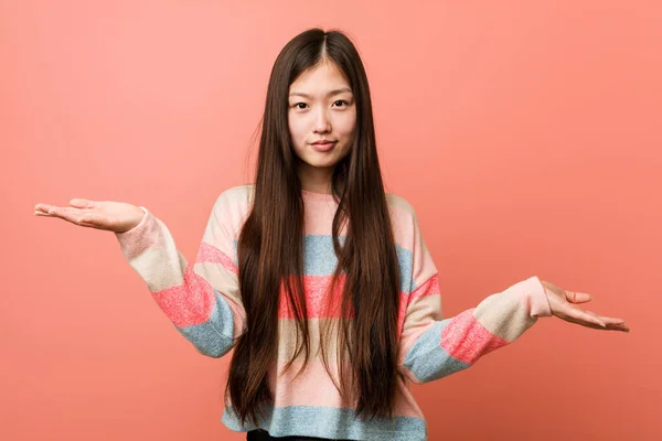 Young cool chinese woman doubting between two options.