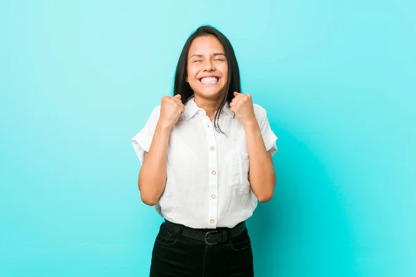 Молодая Латиноамериканка Прислонилась Синей Стене Поднимая Кулак Чувствуя Себя Счастливой — стоковое фото