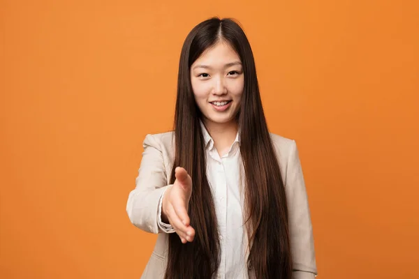 Young business chinese woman stretching hand at camera in greeting gesture.