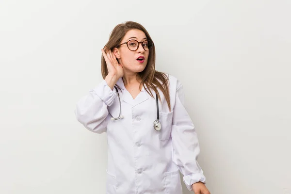 Jonge Dokter Vrouw Tegen Een Witte Muur Proberen Een Roddel — Stockfoto