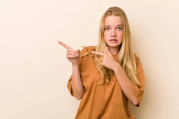 Cute and natural teenager woman shocked pointing with index fingers to a copy space.