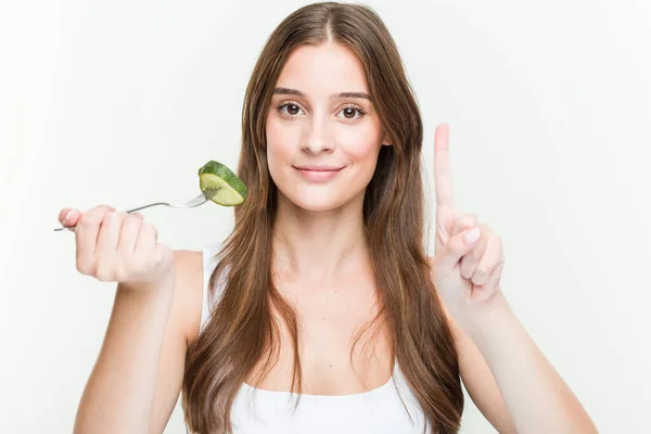 Young Caucasian Woman Eating Cucumber Showing Number One Finger — ストック写真