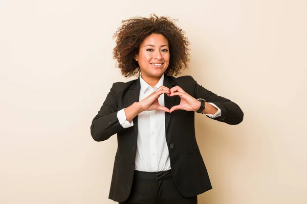 Young business african american woman smiling and showing a heart shape with hands.