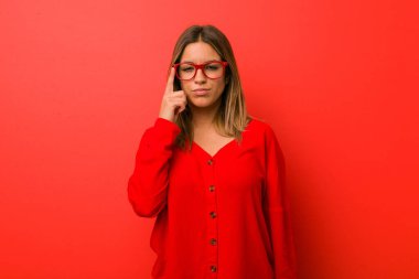 Genç otantik karizmatik gerçek insanlar kadın parmak ile tapınak işaret bir duvara karşı, düşünme, bir görev üzerinde duruldu.