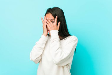 Genç ve güzel İspanyol kadın parmaklarının arasından korkmuş ve gergin bir şekilde göz kırpıyor..