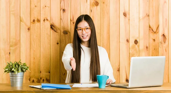 Joven Mujer China Estudiando Escritorio Estirando Mano Cámara Gesto Saludo —  Fotos de Stock