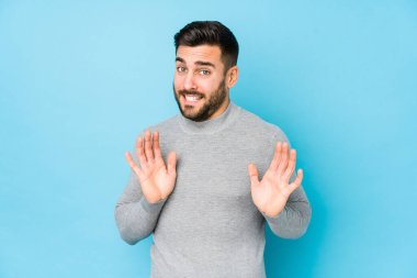 Mavi arka planda genç beyaz bir adam dışlanmış, tiksinti belirtisi gösteren birini reddediyor..