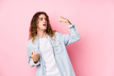 Uzun saçlı adam yalnız poz veriyor. Zaferden sonra yumruğunu kaldırıyor. Kazanan kavram..