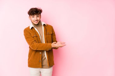 Pembe arka planda yalnız poz veren genç bir Arap.