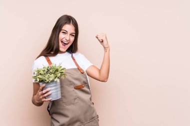 Genç bahçıvan Kafkas kadın, zafer kazandıktan sonra bitkiyi soyutlayan bir yumruk tutuyor..