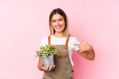 Pembe arka plandaki beyaz bir kadın tişört fotokopi odasını elle gösteriyor, gururlu ve kendinden emin.