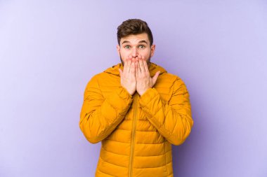 Mor arka planda izole edilmiş genç adam şok olmuş, ağzı ellerle kaplanmış, yeni bir şey keşfetmeye hevesli..