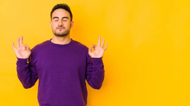 Beyaz tenli genç adam sarı fırında izole edilmiş yoğun çalışma gününden sonra dinleniyor. Yoga yapıyor..