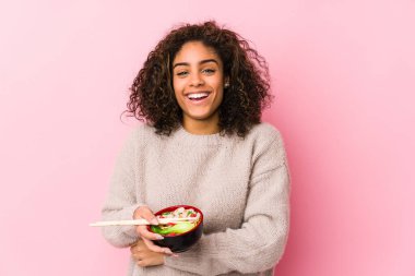 Genç Afrikalı Amerikalı kadın erişte yiyor, gülüyor ve eğleniyor..