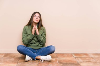 Genç, beyaz bir kadın yerde oturuyor. Kafasında bir plan kuruyor. Bir fikir kuruyor..