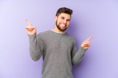 Mor arka planda izole edilmiş genç beyaz adam farklı kopya alanlarını gösteriyor, birini seçiyor, parmağıyla gösteriyor..
