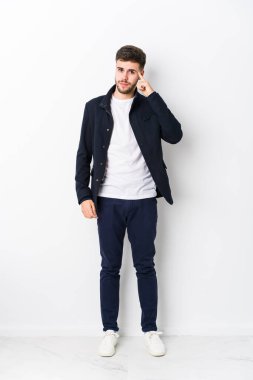 Tam vücut Kafkasyalı genç adam, tapınağı parmağıyla göstererek, düşünerek, bir göreve odaklanmış..