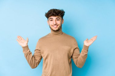 Münzevi genç Arap adam kollarıyla ölçek yapar, mutlu ve kendinden emin hisseder..