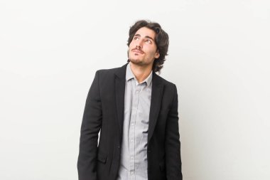 Genç iş adamı beyaz bir arkaplan karşısında hedeflerine ve amaçlarına ulaşmayı hayal ediyor.