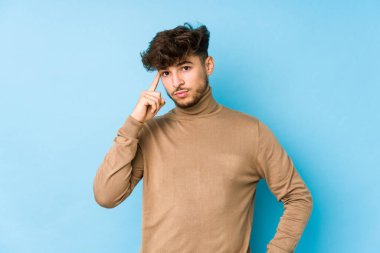 Genç Arap adam, tapınağı parmağıyla göstererek, düşünerek, bir göreve odaklandı..