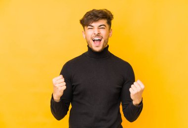 Sarı arka planda yalnız yaşayan genç bir Arap kaygısız ve heyecanlı bir tezahürat yapıyor. Zafer konsepti.