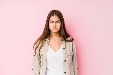 Pembe arka planda poz veren beyaz bir kadın yanakları patlatır, yorgun bir ifadeye sahiptir. Yüz ifadesi kavramı.