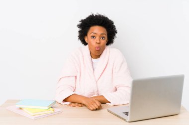 Orta yaşlı Afrikalı Amerikalı kadın evde tek başına çalışıyor omuz silkiyor ve gözleri açık..