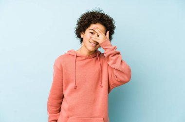 Afrikalı Amerikalı küçük çocuk kameraya parmaklarıyla göz kırpıyor, yüzünü kapatmaktan utanıyor..