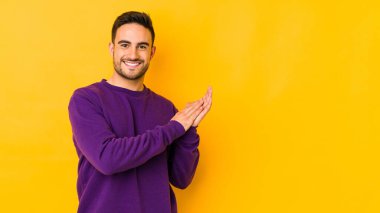 Kafkasyalı genç adam sarı fırında izole edilmiş enerjik ve rahat hissediyor ellerini ovuşturuyor kendinden emin..