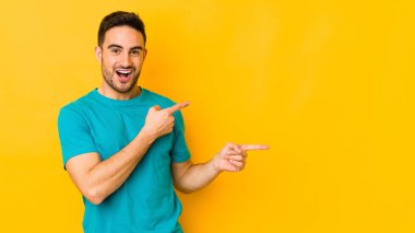 Sarı fırında izole edilmiş genç beyaz bir adam işaret parmağıyla fotokopi alanını işaret ederek heyecan ve arzusunu ifade ediyor..