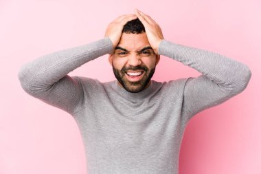 Pembe arka planda yaşayan genç bir latin adam neşeli bir şekilde ellerini başının üstünde tutuyor. Mutluluk kavramı.