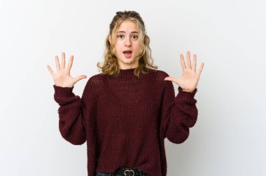 Beyaz arka plandaki genç beyaz kadın gökyüzüne haykırıyor, yukarı bakıyor, hayal kırıklığına uğramış..