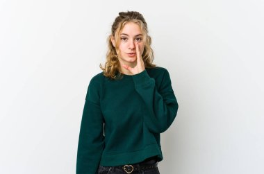 Beyaz arka plandaki genç beyaz kadın gizli bir sıcak fren haberi veriyor ve yan bakıyor.