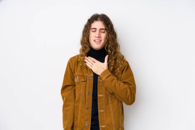 Uzun saçlı adam yalnız poz veriyor. Kahkahalar atıyor. Elini göğsüne koyuyor..