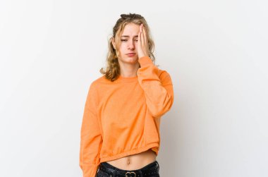 Beyaz arka plandaki genç beyaz kadın yorgun ve uykulu. Elini başının üstünde tutuyor..