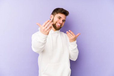 Mor arka planda izole edilmiş genç beyaz adam sanki seni davet ediyormuş gibi seni işaret ediyor..