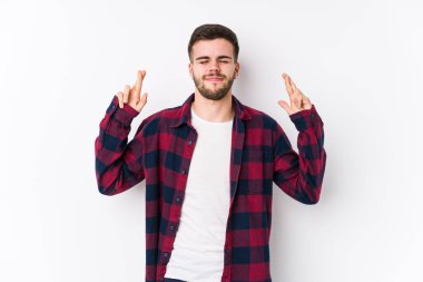 Beyaz arka planda poz veren beyaz tenli genç adam şans dilemek için şans diliyor.