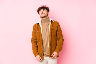 Pembe arka planda yalnız poz veren genç bir Arap.