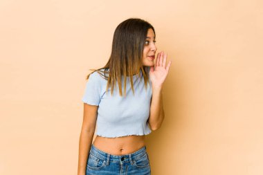 Bej arka planda izole edilmiş genç bir kadın gizli bir fren haberinin olduğunu ve kenara baktığını söylüyor.